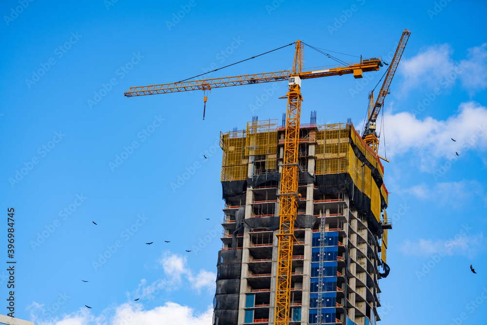 Highrise construction building with cranes on blue sky