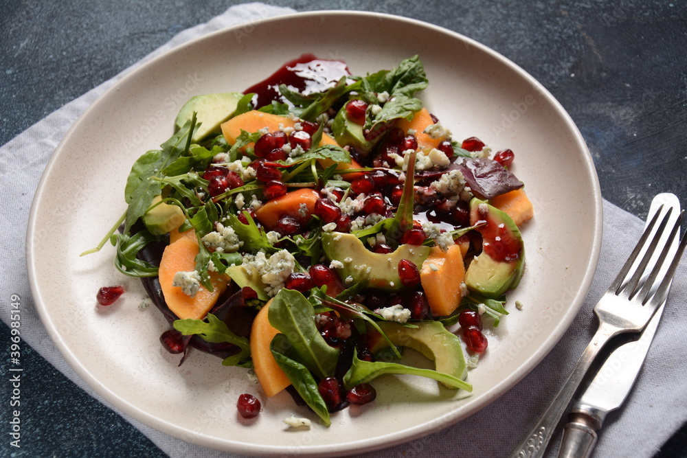 Healthy salad persimmon, blue cheese, spinach, arugula, lettuce leaves on white plate Healthy salad persimmon, blue cheese, spinach, arugula, lettuce leaves on white plate