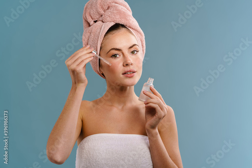 Woman in towel taking care of her skin with serum