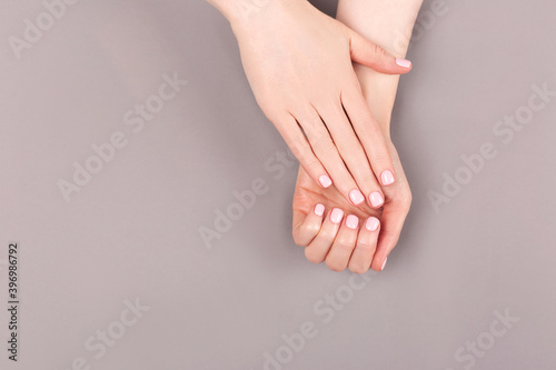 Manicure and nail care concept. Minimal composition of the woman hands on the grey background. Classic pink nail polish. Flat lay  top view.