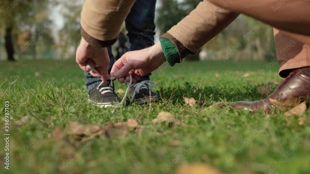 Father tying son's shoelaces, taking care of child, happy fatherhood, upbringing Father tying son's shoelaces, taking care of child, happy fatherhood, upbringing