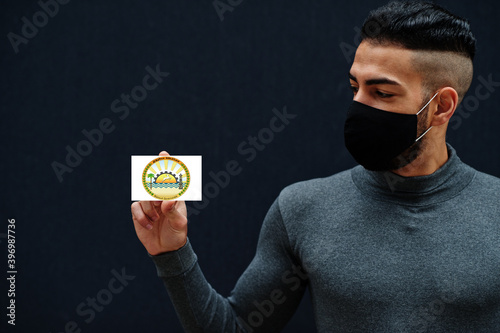 Egyptian man in gray turtleneck and black face protect mask show Matruh flag isolated background. Governorates of Egypt coronavirus concept. photo