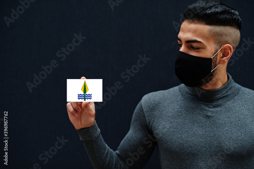 Egyptian man in gray turtleneck and black face protect mask show New Valley flag isolated background. Governorates of Egypt coronavirus concept. photo