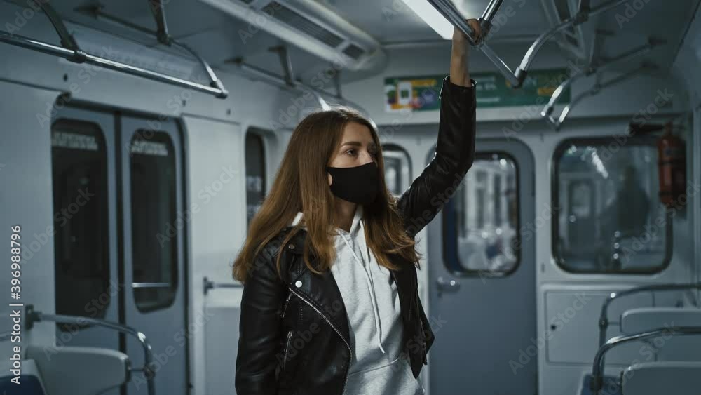 Urban travel. Young woman riding in subway carriage, standing alone, preening hair Urban travel. Young woman riding in subway carriage, standing alone, preening hair
