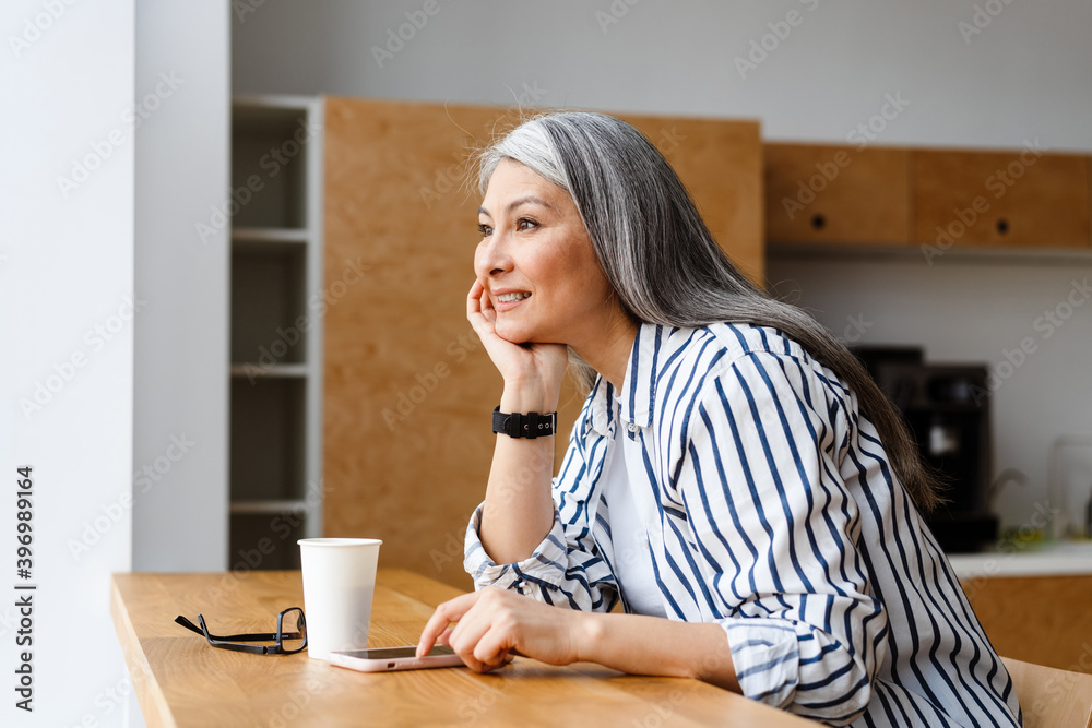 Happy white-haired mature woman drinking coffee and using mobile phone Happy white-haired mature woman drinking coffee and using mobile phone