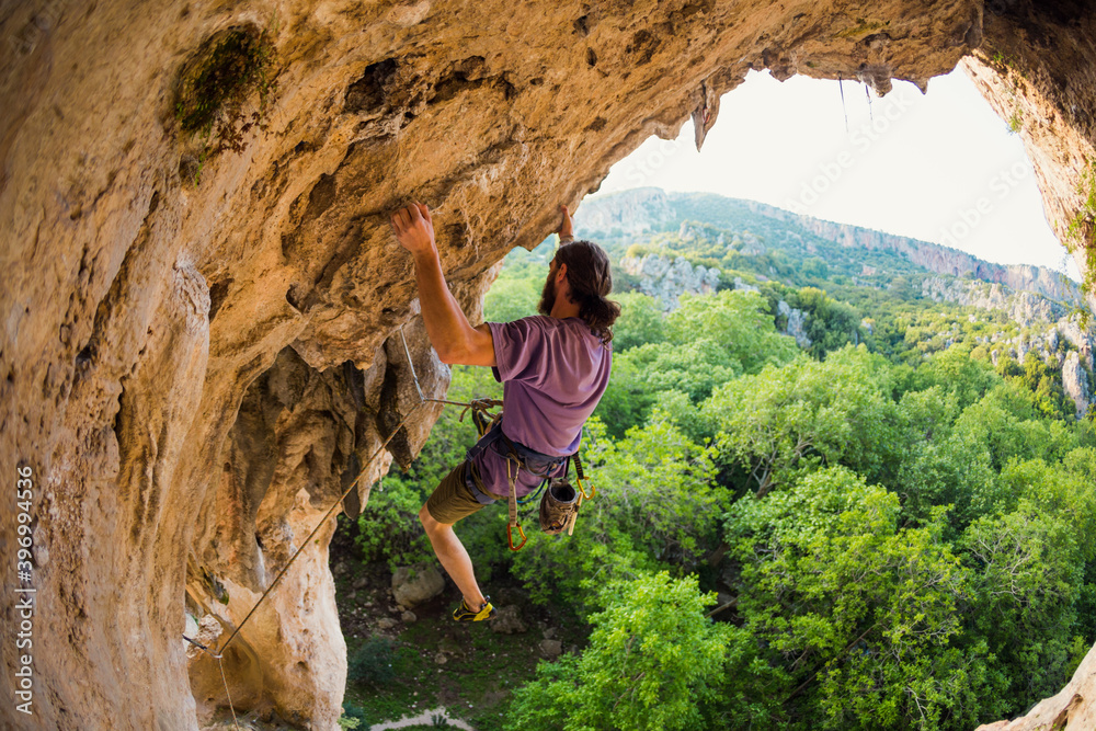 Naklejka premium Rock climber climbs into the cave, Rock in the form of an arch
