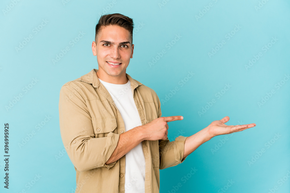 Young caucasian handsome man isolated excited holding a copy space on palm. Young caucasian handsome man isolated excited holding a copy space on palm.