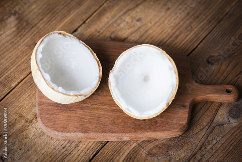 cut half coconut and fresh coconuts on old wooden table for food.
