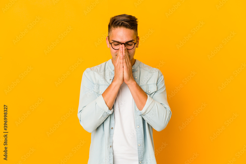 Young handsome caucasian man isolated holding hands in pray near mouth, feels confident. Young handsome caucasian man isolated holding hands in pray near mouth, feels confident.