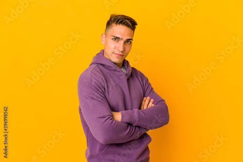 Young handsome caucasian man isolated who feels confident, crossing arms with determination.