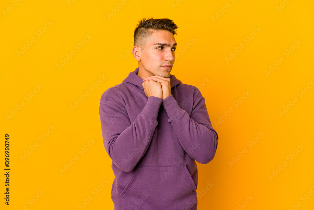 Young handsome caucasian man isolated keeps hands under chin, is looking happily aside. Young handsome caucasian man isolated keeps hands under chin, is looking happily aside.