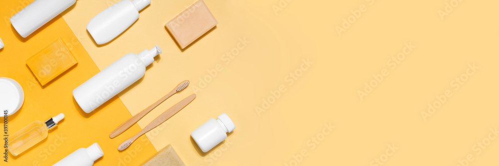 Banner with cosmetic mock up. Tubes with cream, glass bottle with oil, toothbrush, soap, dispensers and jars on yellow background. Flat lay copy space Banner with cosmetic mock up. Tubes with cream, glass bottle with oil, toothbrush, soap, dispensers and jars on yellow background. Flat lay copy space