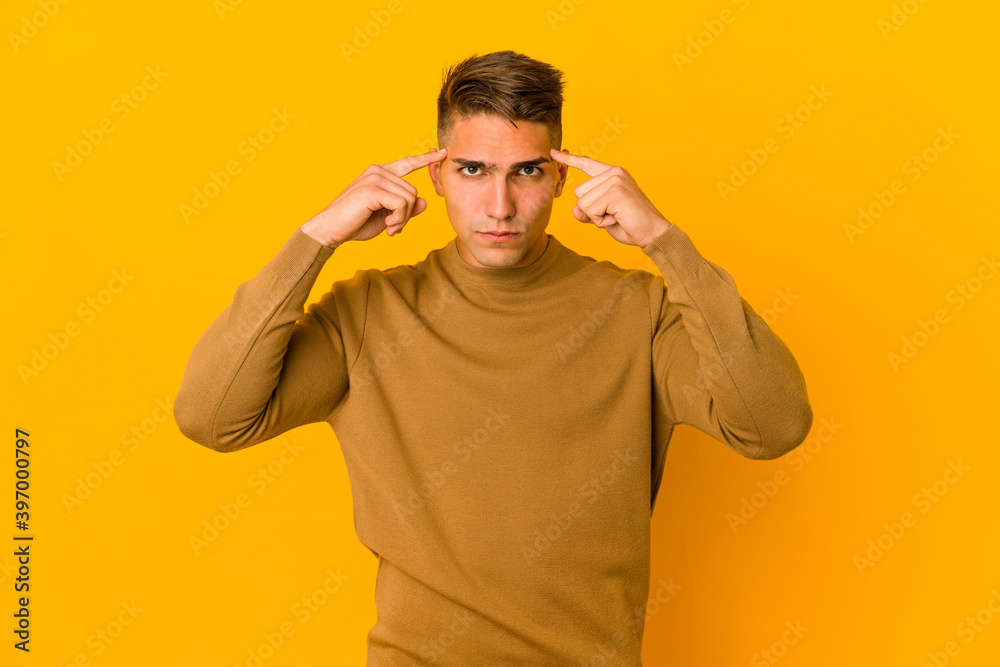 Young handsome caucasian man isolated focused on a task, keeping forefingers pointing head. Young handsome caucasian man isolated focused on a task, keeping forefingers pointing head.