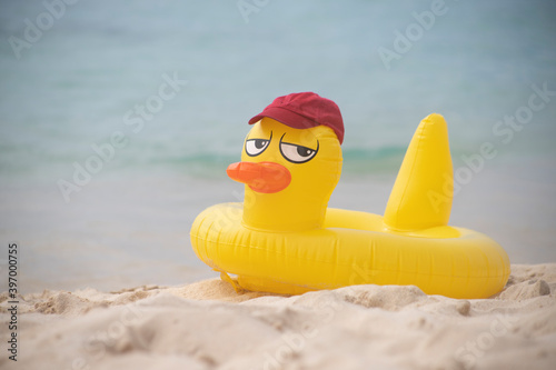 
INFLATABLE YELLOW LIFE DUCK WITH A RED BASEBALL CAP ON THE SHORES OF A VIRGIN CARIBBEAN TROPICAL BEACH