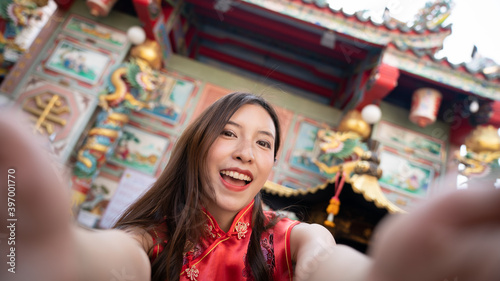 Asian woman wearing red Cheongsam dress at Chinese shrine. Chinese new year concept.