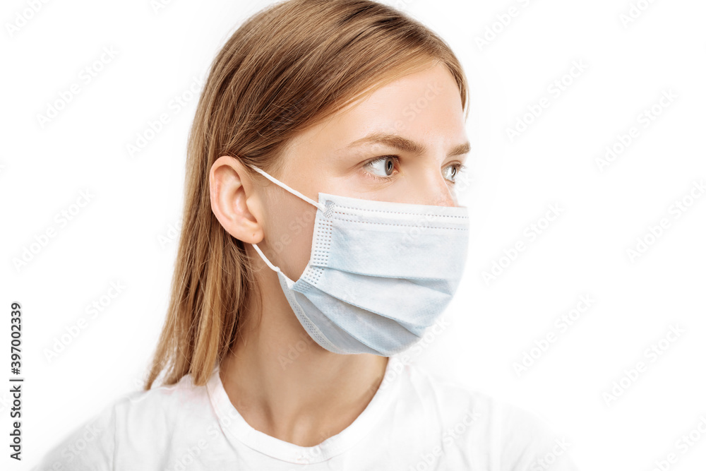 Close-up of a young woman, in a surgical mask on her face, to prevent infection, on an white background, Protection against infectious diseases, coronavirus Close-up of a young woman, in a surgical mask on her face, to prevent infection, on an white background, Protection against infectious diseases, coronavirus