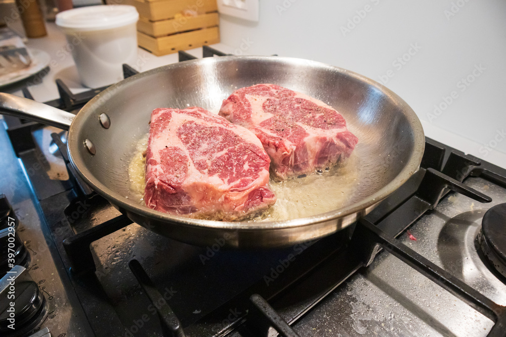 Ribeye beef steak in a stainless steel pan with butter. Ribeye beef steak in a stainless steel pan with butter.