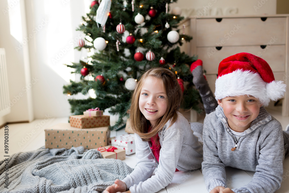 Christmas - Girl and boy lying in front of a Christmas tree celebrating Christmas Christmas - Girl and boy lying in front of a Christmas tree celebrating Christmas
