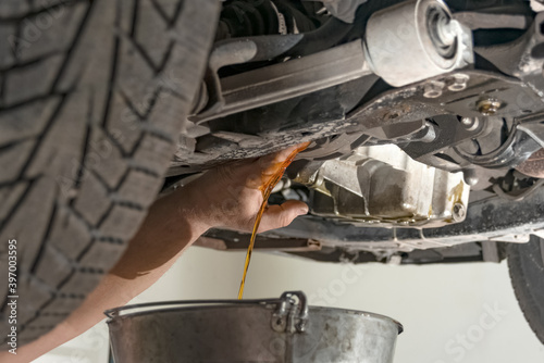 A man helps to drain engine oil from an engine reservoir in a car.