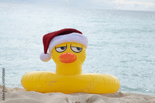 
YELLOW INFLATABLE LIFEGUARD DUCK WITH SANTA CLAUS HAT ON THE SHORES OF A CARIBBEAN BEACH ON A SUNNY DAY