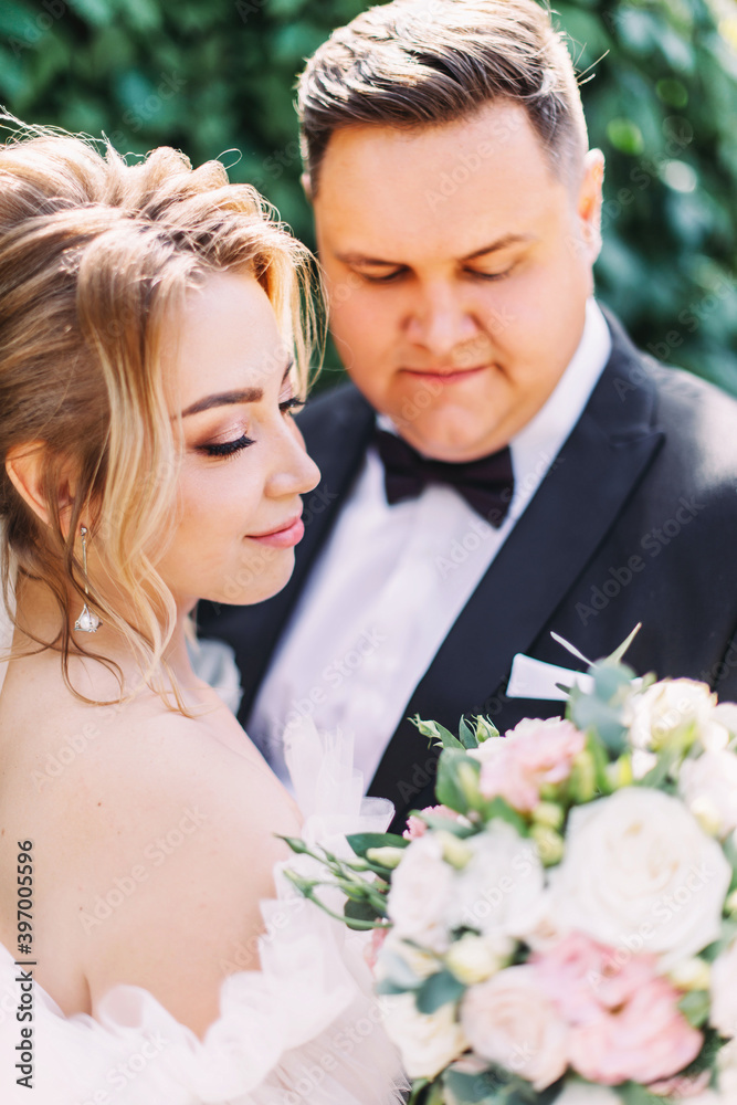 Wedding couple hugs, elegant groom and tender bride with luxurious bouquet of roses