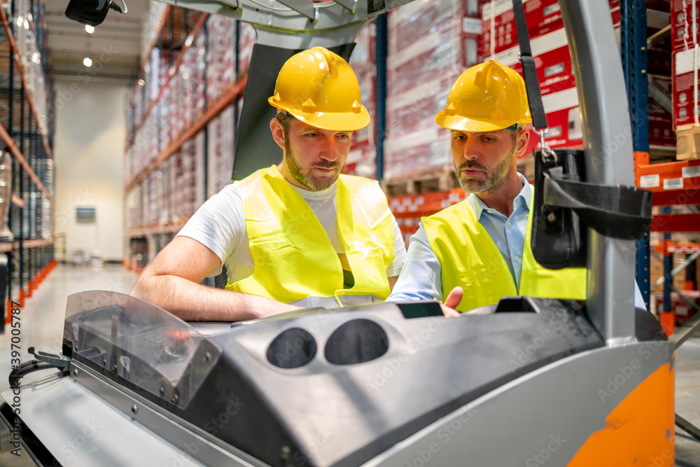 Warehouse worker learns how to use forklift with instructor Warehouse worker learns how to use forklift with instructor