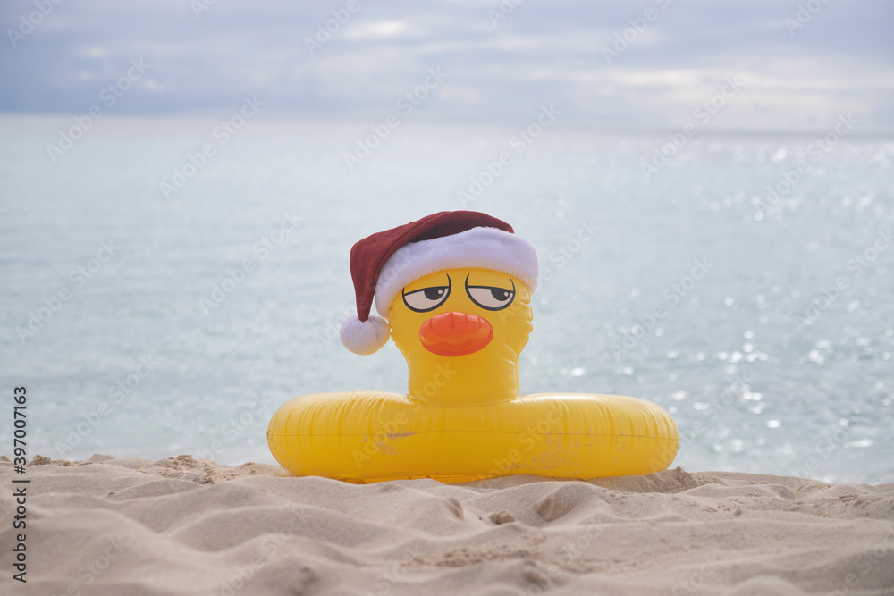 Naklejka premium YELLOW INFLATABLE LIFEGUARD DUCK WITH SANTA CLAUS HAT ON THE SHORES OF A CARIBBEAN BEACH ON A SUNNY DAY