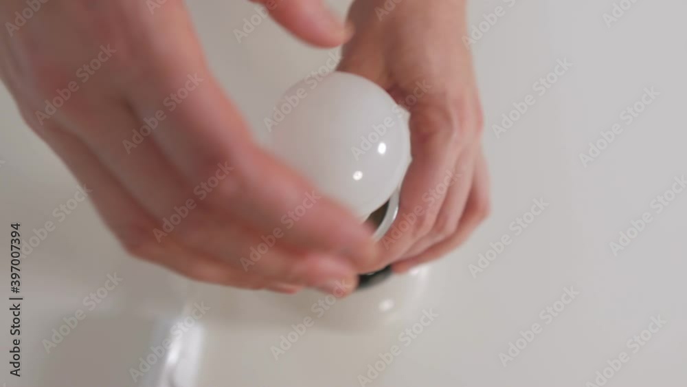 Close-up of a woman's hand replacing an led light bulb in a table lamp