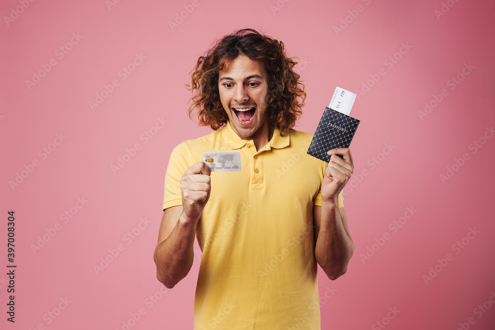 Delighted handsome guy posing with credit card and passport Delighted handsome guy posing with credit card and passport