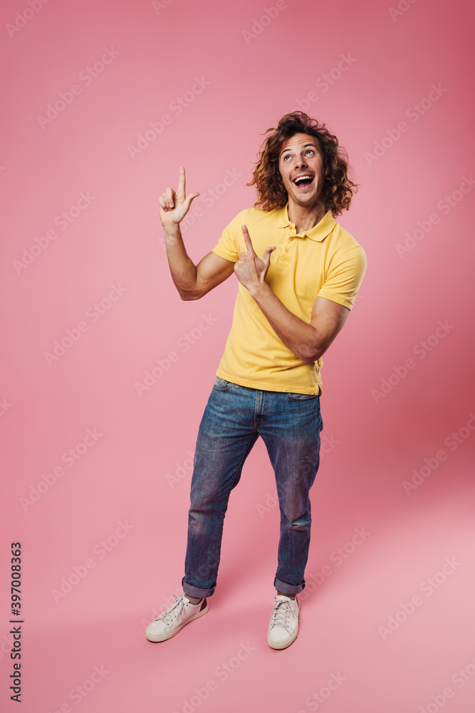 Happy handsome caucasian guy smiling and pointing fingers upward Happy handsome caucasian guy smiling and pointing fingers upward