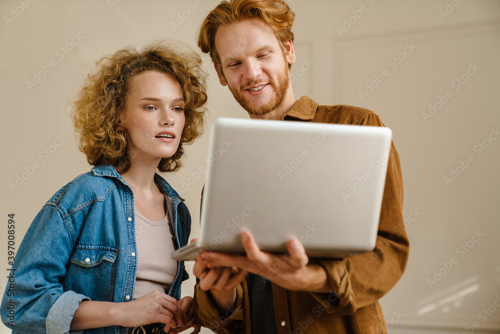 Attractive young couple using laptop while standing Attractive young couple using laptop while standing