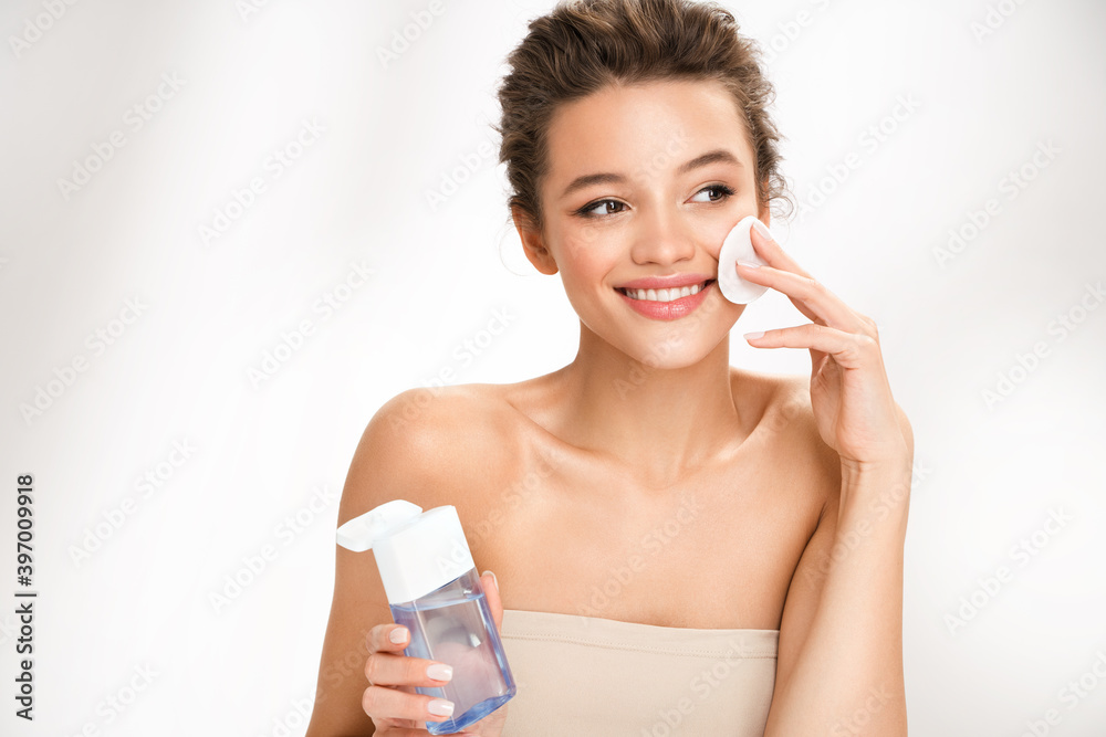 Woman removing makeup, holds cotton pads near face. Photo of woman with perfect skin on white background. Beauty and skin care concept Woman removing makeup, holds cotton pads near face. Photo of woman with perfect skin on white background. Beauty and skin care concept