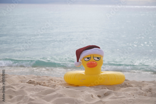  YELLOW INFLATABLE LIFEGUARD DUCK WITH SANTA CLAUS HAT ON THE SHORES OF A CARIBBEAN BEACH ON A SUNNY DAY