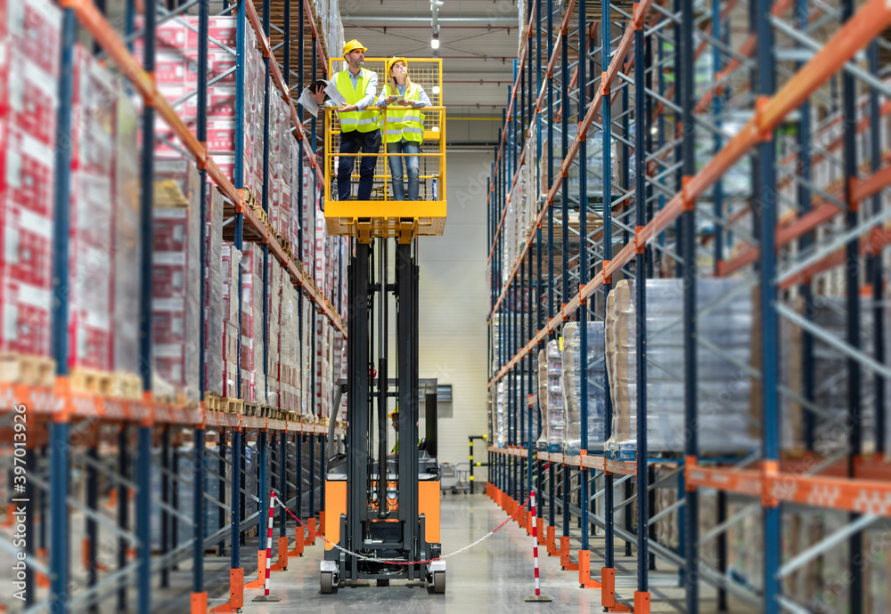 Warehouse workers on the height using lift work platform to check inventory Warehouse workers on the height using lift work platform to check inventory