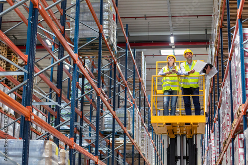 Photography Warehouse workers on lift work platform checking inventory