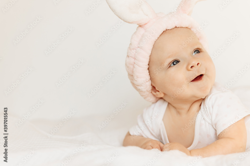 Portrait of wonderful baby girl laying on comfortable bed at home, adorable cute toddler look around with big interest, smiling, childhood and childcare concept