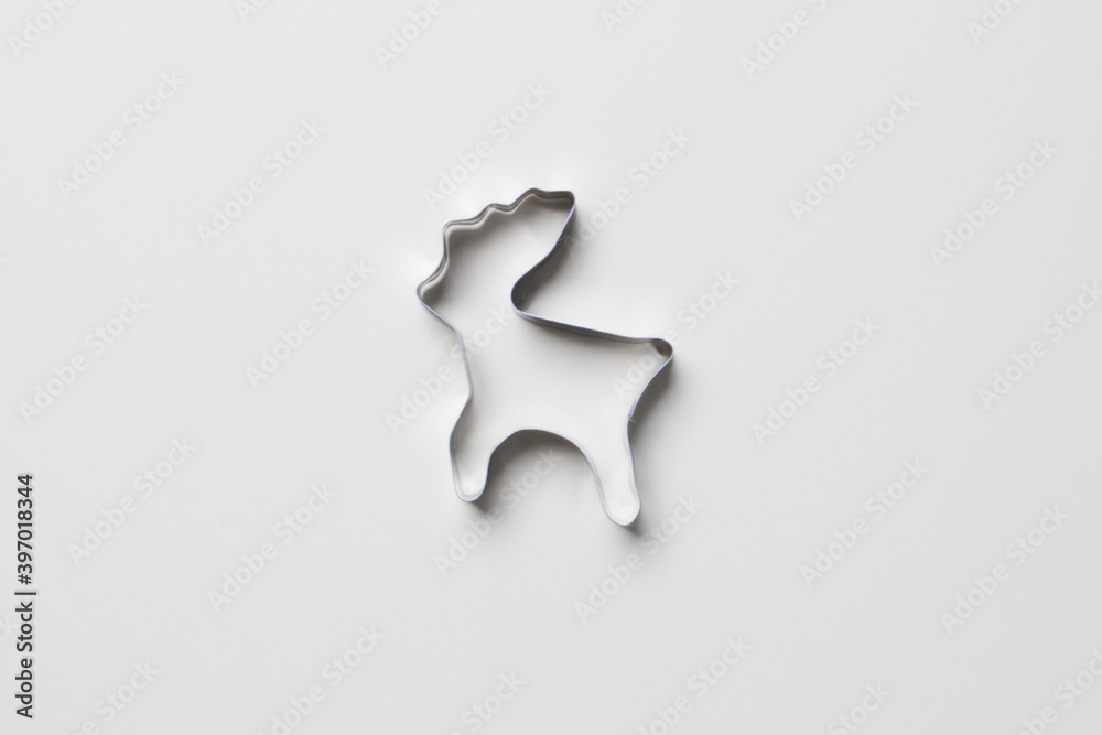 cookie cutter in form of deer on white colored paper background. isolated. close up. mock up