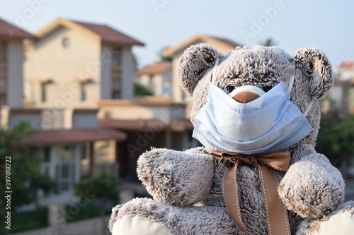 Teddy bear wearing protective face mask outside during home isolation