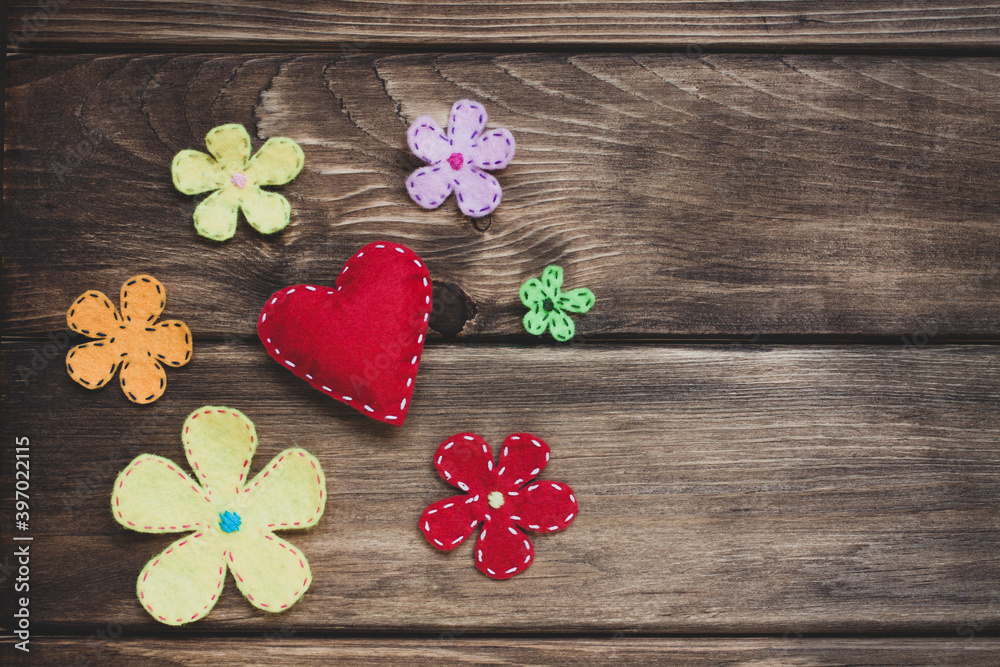 Red felt heart with white stitches and decorative flowers on a vintage wood texture. Love and romantic concept. Red felt heart with white stitches and decorative flowers on a vintage wood texture. Love and romantic concept.