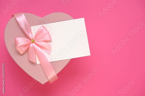 Valentine's day holiday.Pink heart box with bow ,with white card On a pale pink background. Gift heart.Blank postcard.Love and passion concept.Valentine's Day gift.copy space.Mother's day