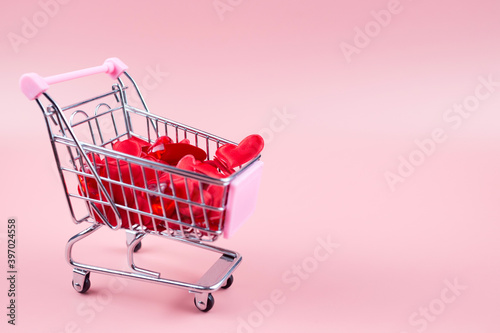 Valentine's Day online Shopping. Shopping cart with hearts on a pink background. 