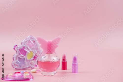 Cosmetics for little girls, baby perfume, lipstick, eye shadow, lip gloss, on a pink background.