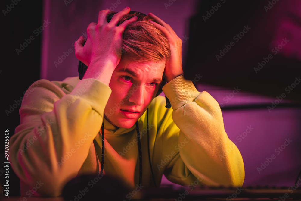 Tensed gamer looking at computer monitor on blurred foreground Tensed gamer looking at computer monitor on blurred foreground