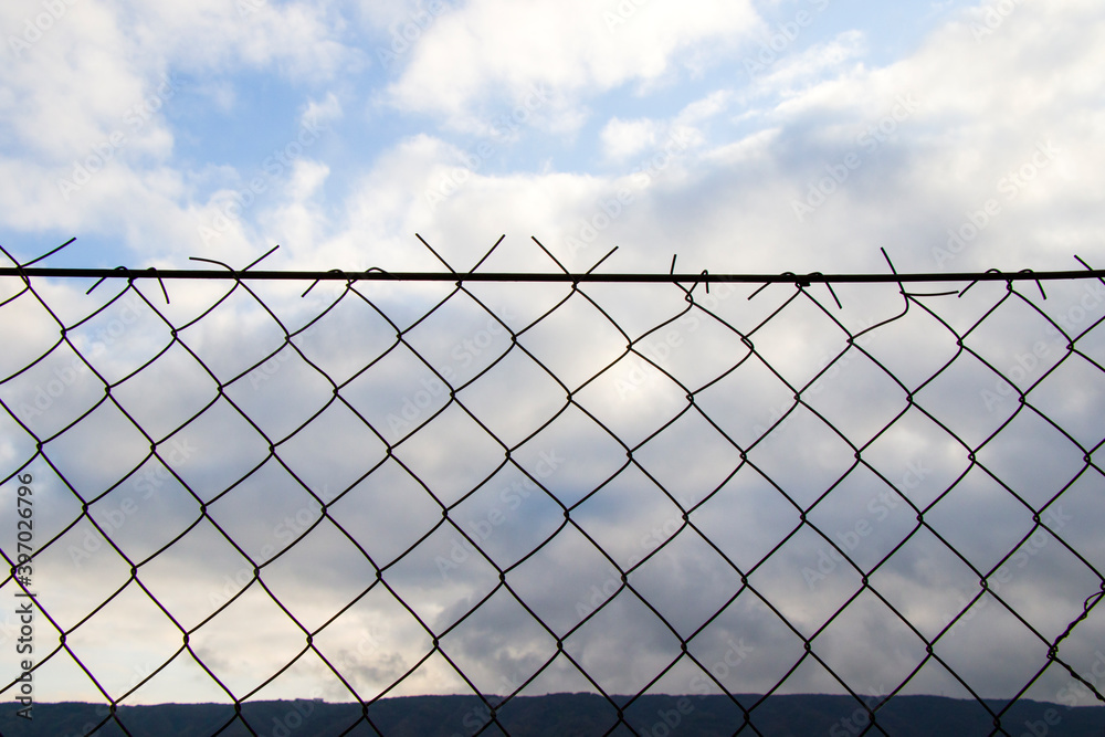 Metal fence background, real fence close-up and texture on sky background Metal fence background, real fence close-up and texture on sky background