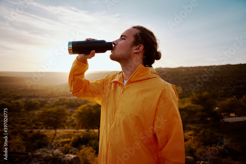 Portrait of young man drinking water from bottle while resting after run