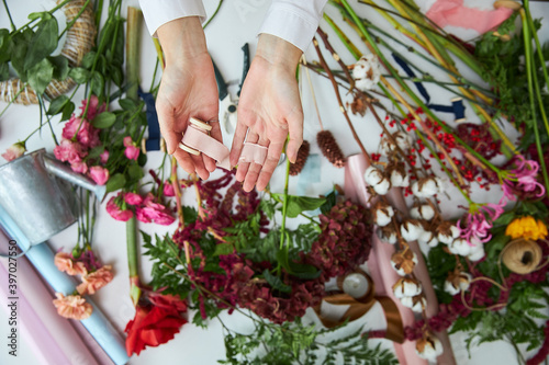 A female florist holds threads for a bouquet. Hands close-up.