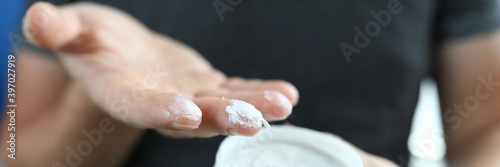 Foto Man's hand holds jar with a white substance inside