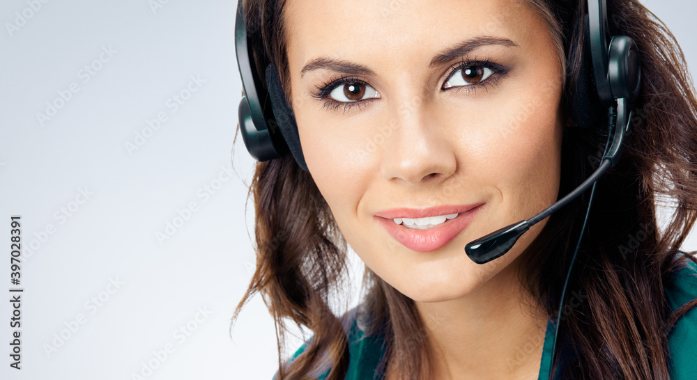 Portrait of smiling beautiful female phone operator in headset, green confident clothing, over grey background. Call center and customer support service studio concept image. Portrait of smiling beautiful female phone operator in headset, green confident clothing, over grey background. Call center and customer support service studio concept image.