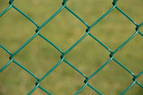 view through green chain link fence onto a green area in the background