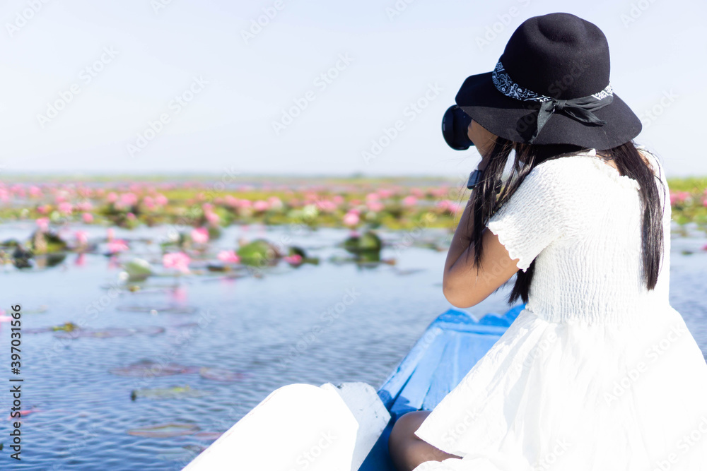 Φωτογραφία Asian woman wearing a white dress, wearing a hat and sitting on a blue boat
